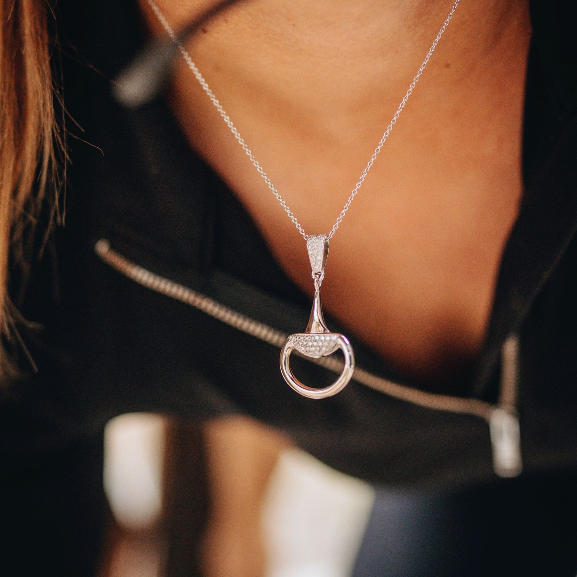 Gold Half Snaffle Pendant. Equestrian horse rider wearing a diamond set half snaffle pendant by Crawford Hill Equestrian Jewellery.