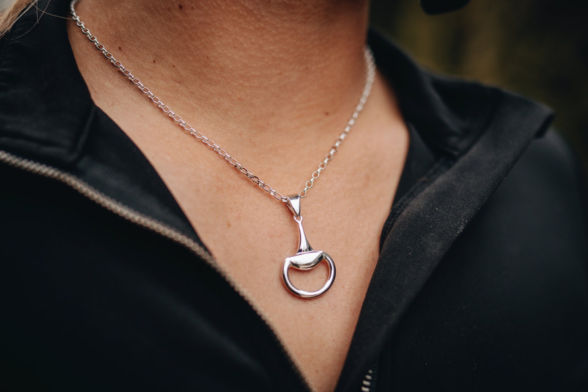 An equestrian wearing a Crawford Hill Half Snaffle Pendant in sterling silver. Paired perfectly with a sterling silver fine oval belcher chain. 