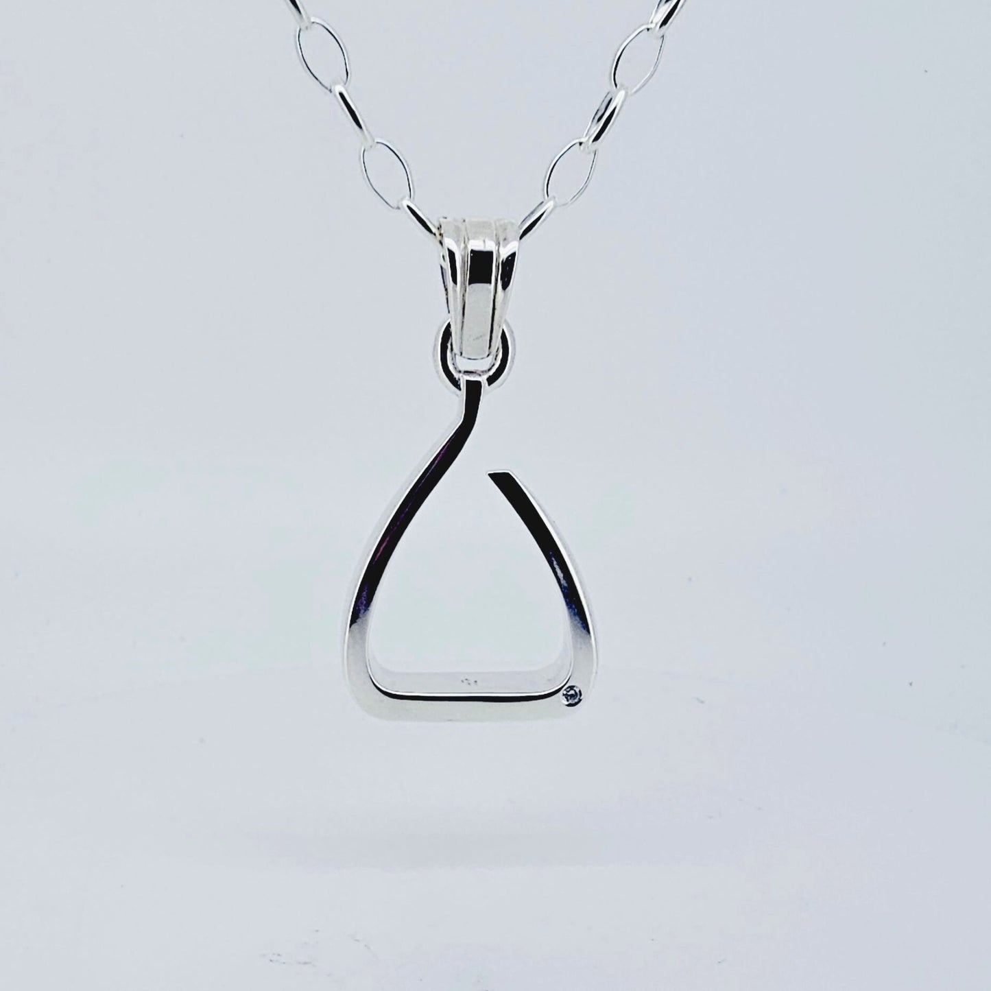 Product shot. Silver jump stirrup necklace. Set with one diamond. Based on the Freejump Stirrup. This is for Horse riders and equestrians. Made by Crawford Hill Equestrian Jewellery.