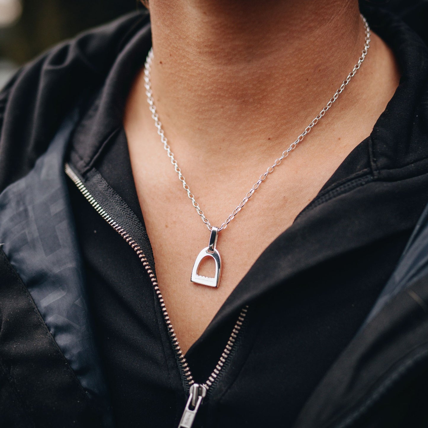 Photo of small silver stirrup necklace worn by a horse rider made by Crawford Hill Equestrian Jewellery.